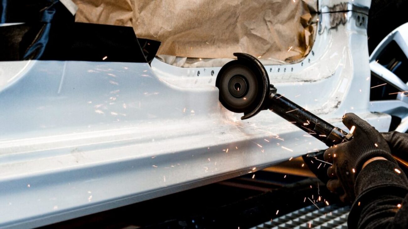 Rost am Auto: Spengler schleift den Schweller eines Autos in der Spenglerei bis aufs blanke Metall ab