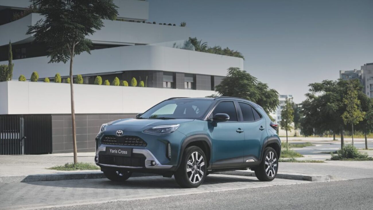 Toyota Yaris Cross Hybrid in Blau vor einem modernen Wohngebäude